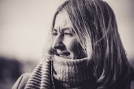 Black and white portrait of a woman wearing a cozy knitted scarf, enjoying the outdoors.
